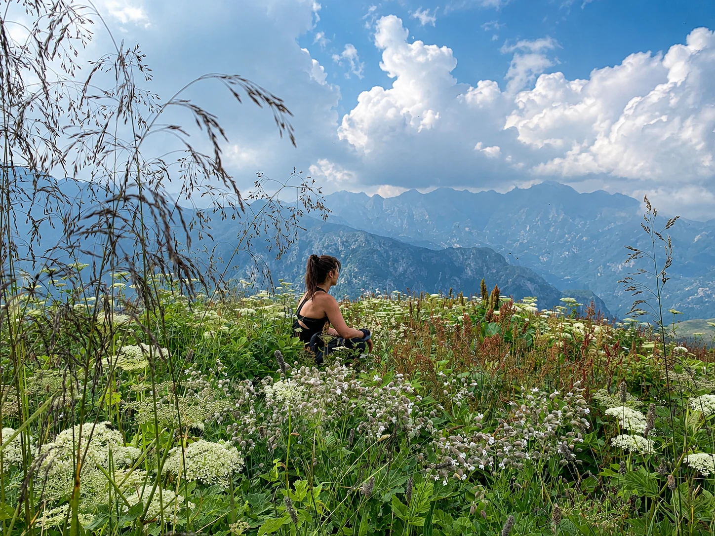 Aysan seated in a mountain meadow overlooking distant peaks