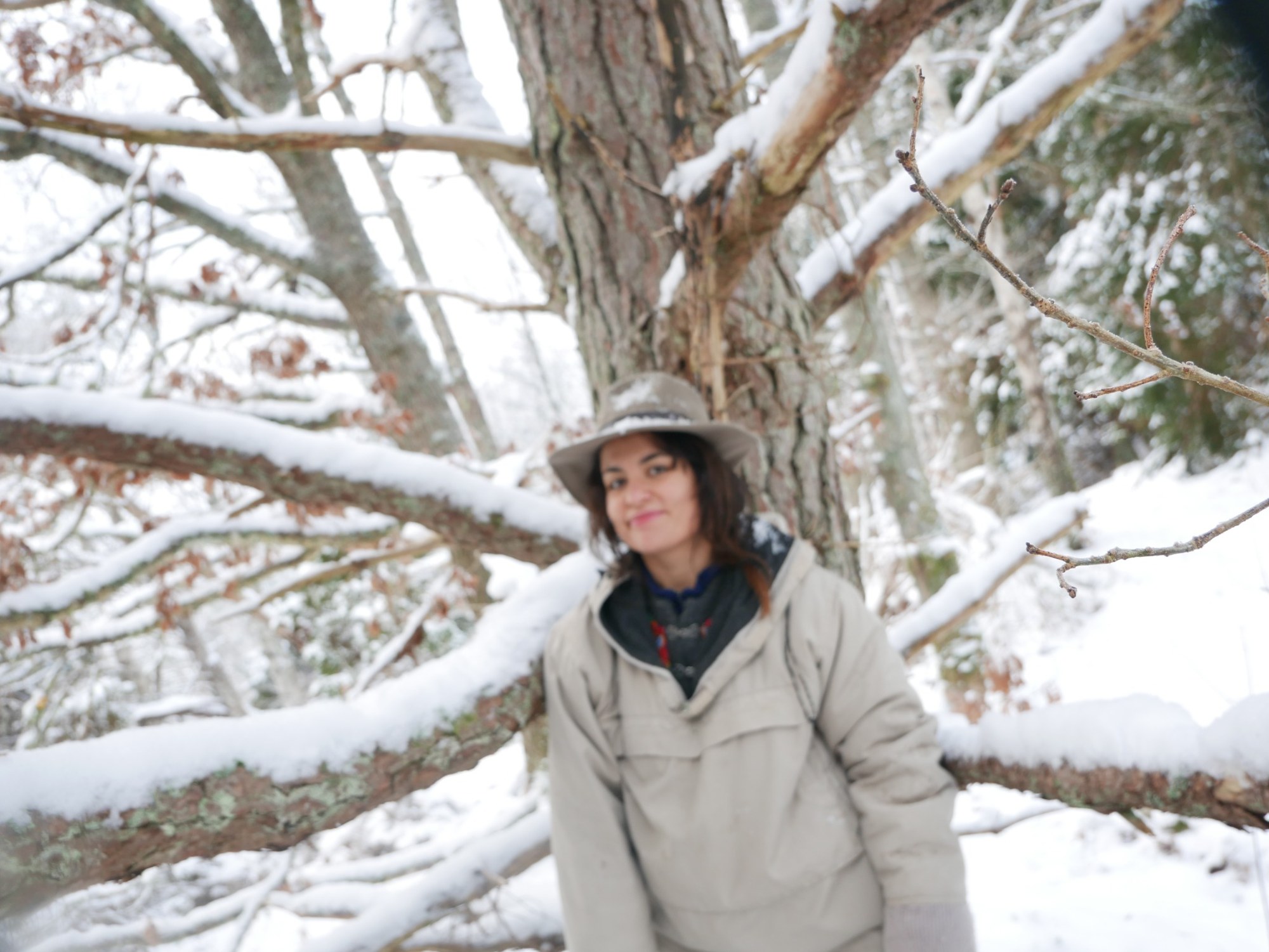Aysan standing beside an old tree in a snowy woodland